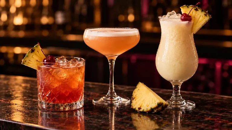 Jungle Bird, French Martini and Piña Colada on a dark bar counter